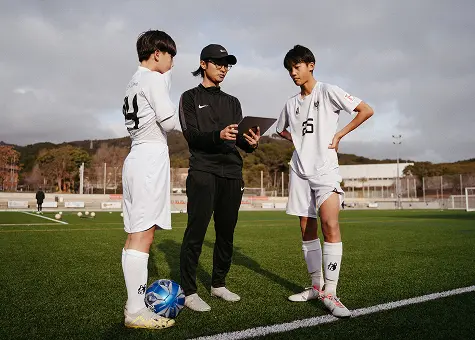entrenador hablando con jóvenes deportistas en un campo de fútbol